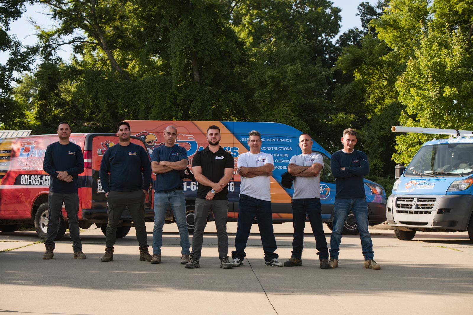 The Dany’s Plumbing crew lined up in front of three lettered company vans in Louisville