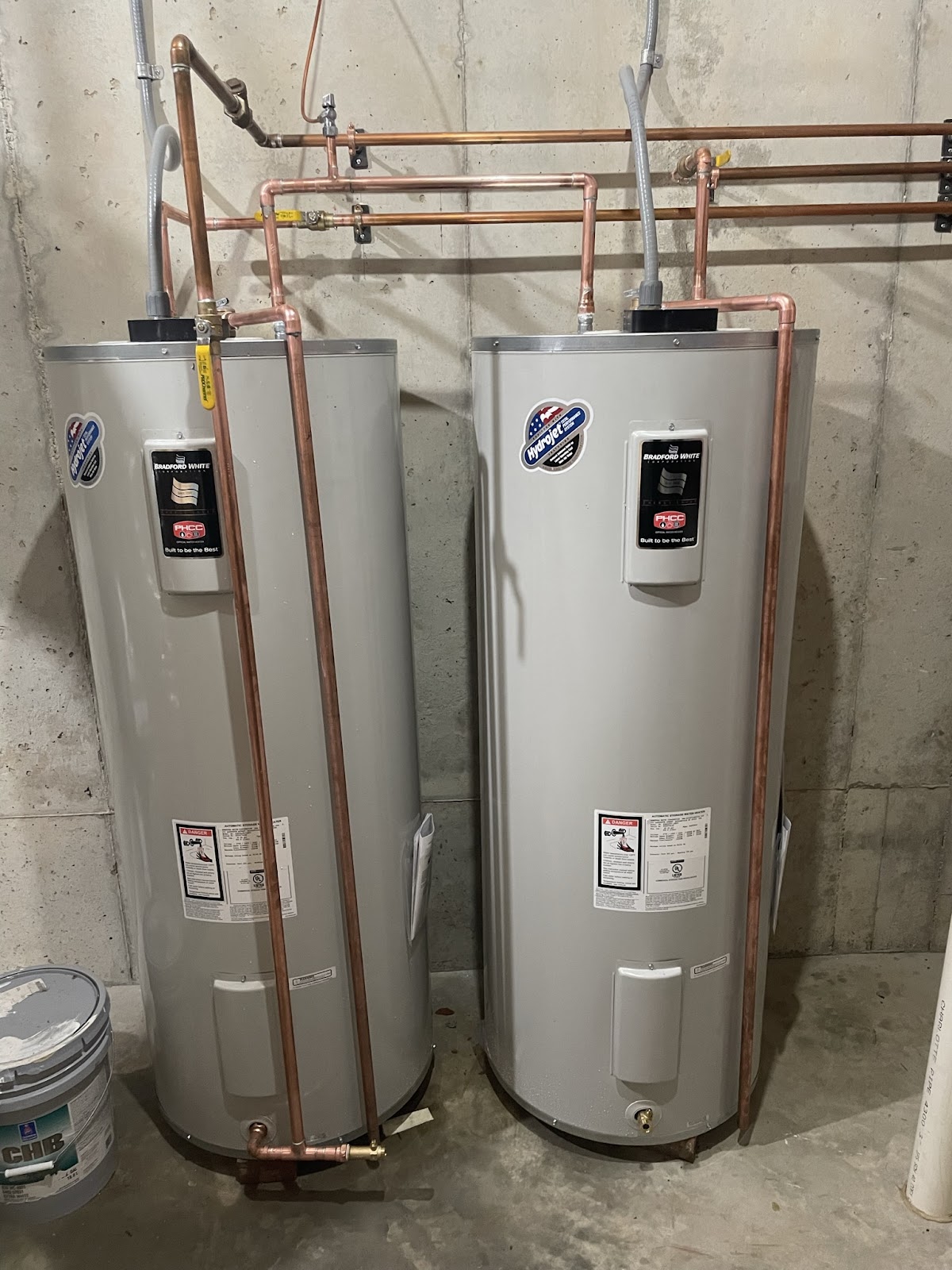 Two new water heaters piped in copper in a basement