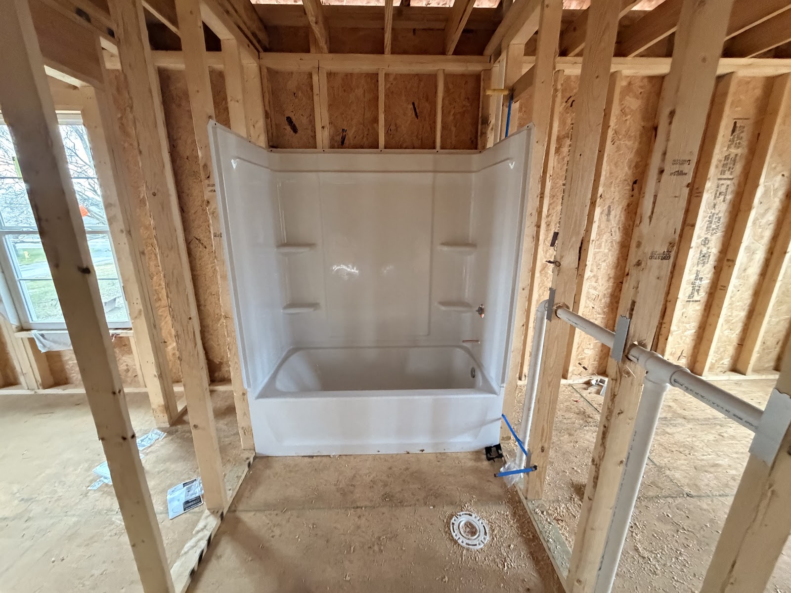 A new tub and shower set in a framed bathroom on a new build