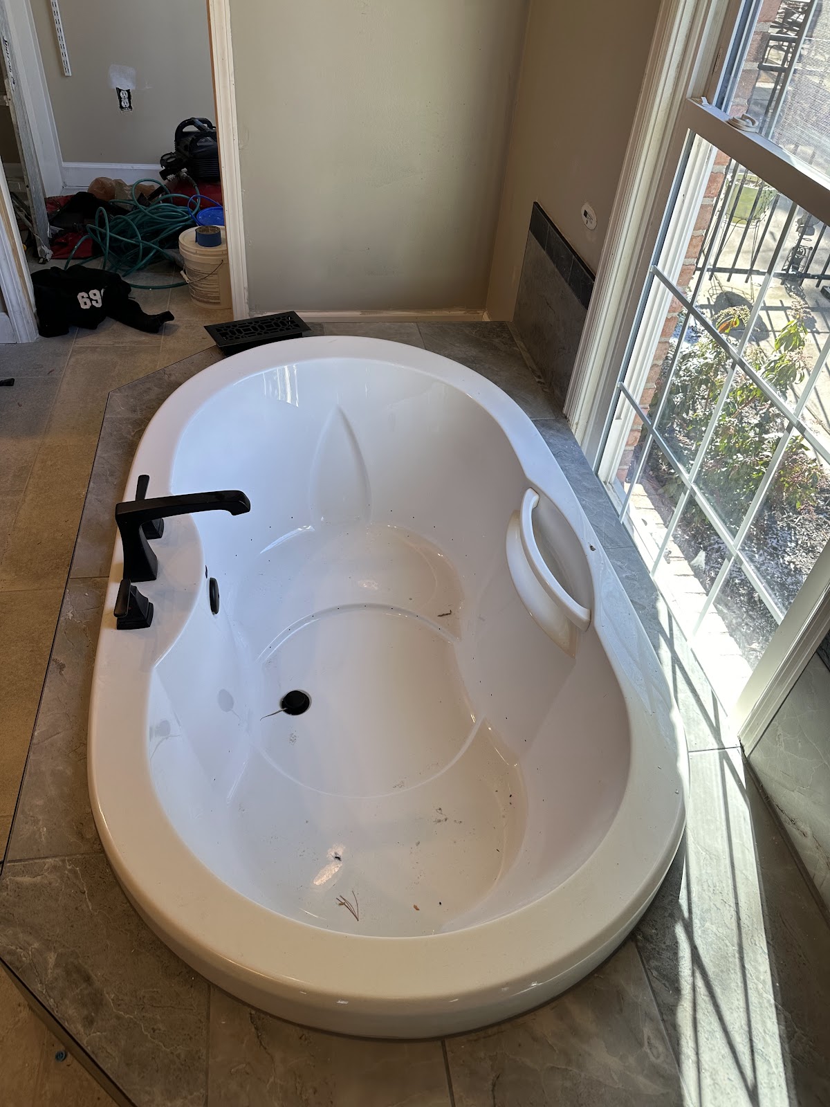A new soaking tub with a black faucet by a bright window