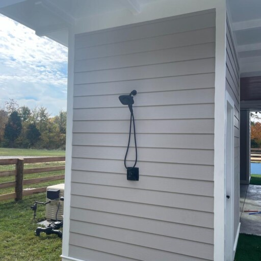 An outdoor shower plumbed on the side of a house