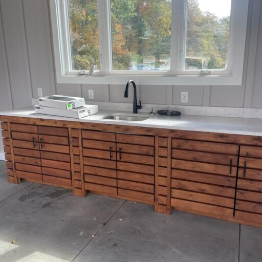 A long wood vanity with a new sink and faucet under a window